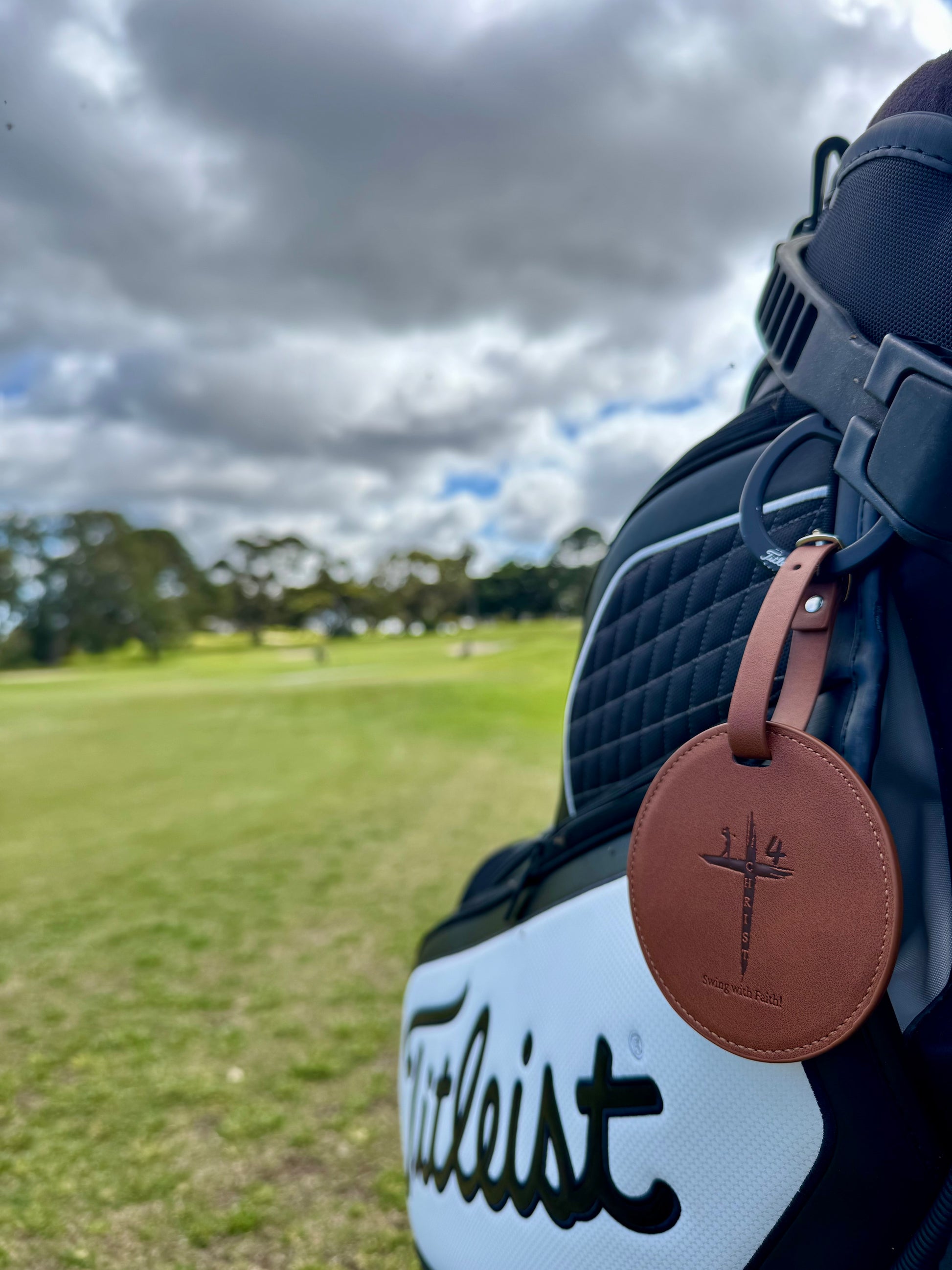 Golf bag with a brown tag featuring a logo on a golf course